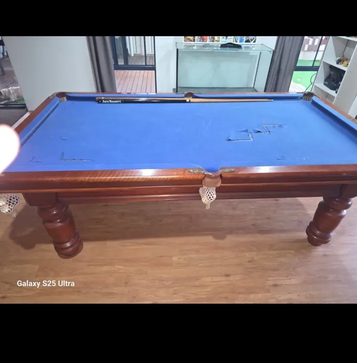 Pool table before reclothing with damaged blue cloth